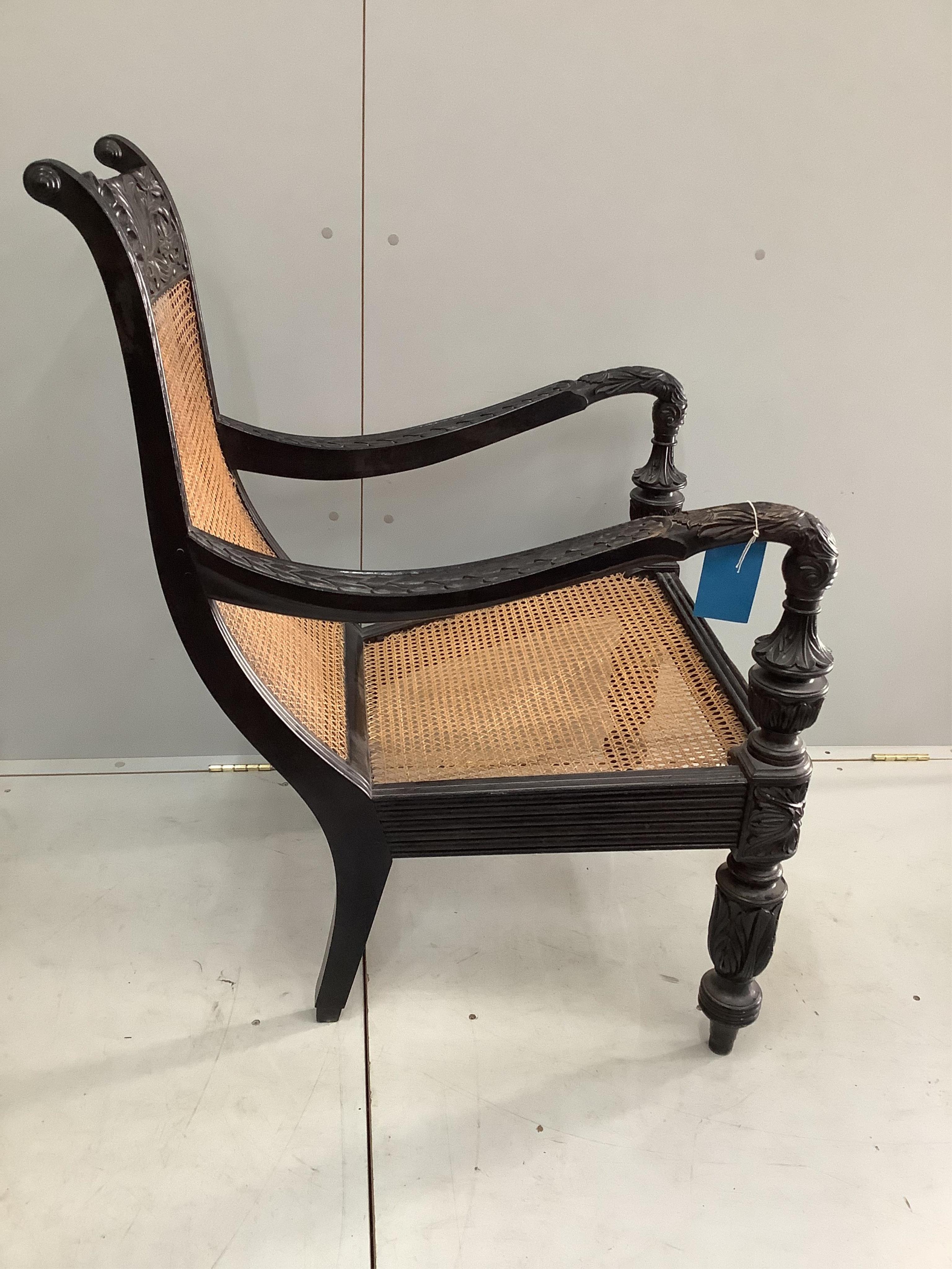 A 19th century Anglo-Indian carved ebony library armchair, with a caned seat and back, width 60cm, depth 76cm, height 102cm. Condition - good